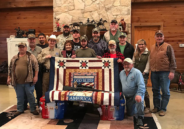 group photo in lodge with God Bless America quilt